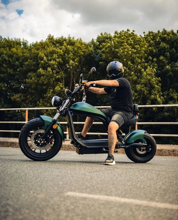 E-Chopper HL 6.0 Phantom in Grün – Seitenansicht mit Fahrer im Stand, Lifestylefoto auf Straße im Sommer